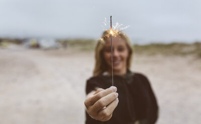 Spain, Aviles, teenage girl holding a sparkler on the beach - MGOF03567