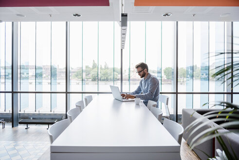 Mann mit Laptop sitzt am Konferenztisch im Büro - DIGF02722