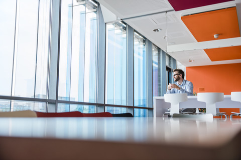 Man with coffee cup sitting in modern office building stock photo