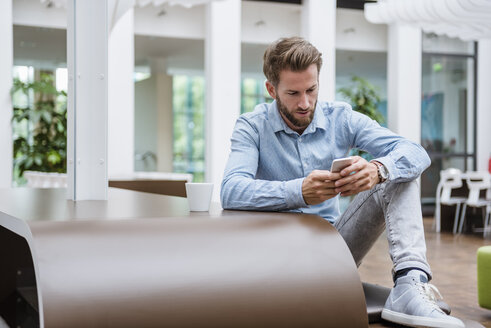 Mann benutzt Mobiltelefon in einem modernen Büro - DIGF02732