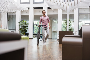 Mann mit Fahrrad zu Fuß im Büro - DIGF02748