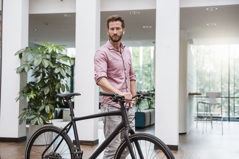 Porträt eines Mannes mit Fahrrad im Büro - DIGF02749