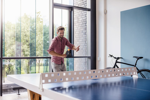 Man in break room of modern office playing table tennis stock photo