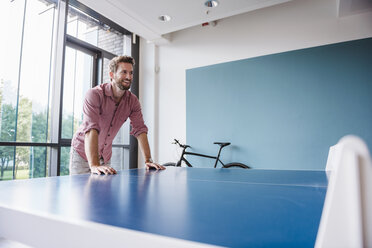 Man in break room of modern office at table tennis table - DIGF02752