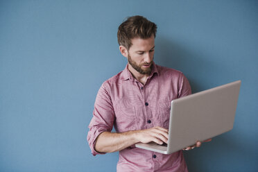 Mann mit Laptop vor blauer Wand - DIGF02757