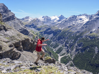 Italy, Lombardy, Sondrio, hiker jumping with view to Stelvio Pass and Ortler - LAF01881