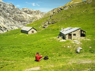 Italy, Lombardy, Sondrio, hiker resting on alpine meadow on the way to Umbrail Pass - LAF01882
