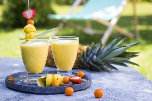 Two glasses of tropical smoothie with pineapple, mango, coconut milk and coconut flakes - YFF00672