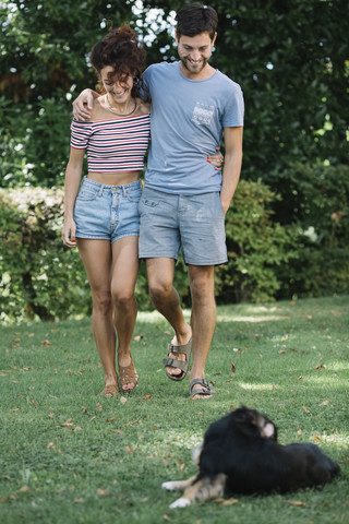 Verliebtes Paar mit Hund beim Spaziergang in einem Park, lizenzfreies Stockfoto