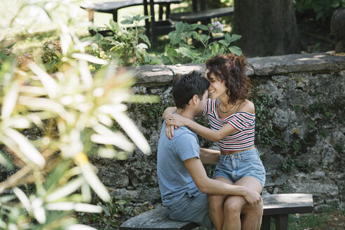 Verliebtes Paar, das sich auf einer Bank im Park umarmt - ALBF00156