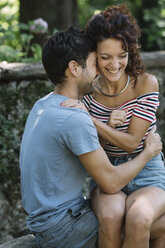 Verliebtes Paar, das sich auf einer Bank im Park umarmt - ALBF00160