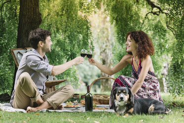 Couple with dog having a picnic in a park drinking red wine - ALBF00161