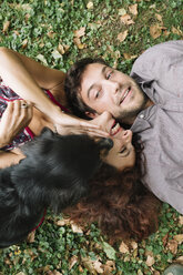 Happy couple in love with dog lying on a meadow - ALBF00170