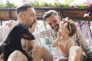Happy gay couple with daughter and dog on balcony - MRAF00223