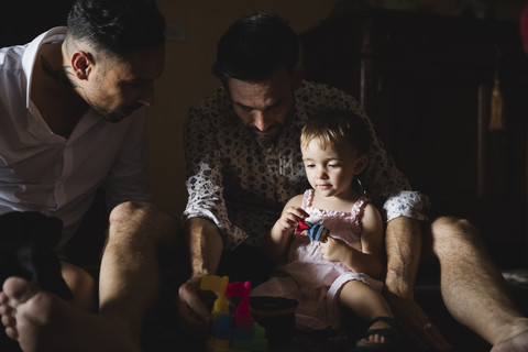 Gay couple playing with their little daughter at home stock photo