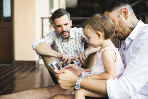 Homosexuelles Paar mit Tochter auf dem Balkon mit digitalem Tablet - MRAF00243