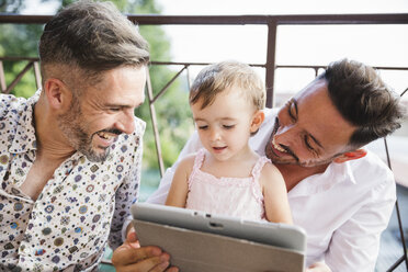 Happy gay couple with daughter on balcony using digital tablet - MRAF00246