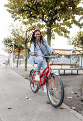 Spanien, Gijon, junge Frau fährt mit dem Fahrrad in der Stadt - MGOF03570