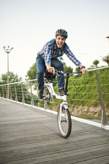 Young man doing tricks with a folding bike - RAEF01932