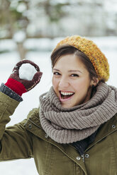 Portrait of laughing woman holding snowball - ZEDF00802