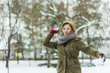Portrait of woman throwing snowball - ZEDF00803