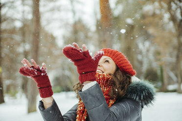 Happy woman catching snowflakes - ZEDF00804