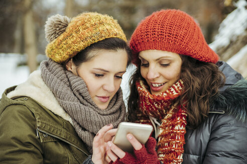 Zwei Freunde im Schnee schauen auf ihr Handy - ZEDF00822