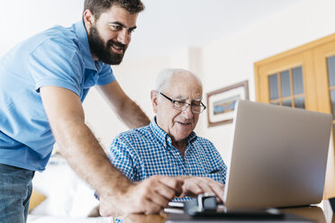Erwachsener Enkel bringt seinem Großvater den Umgang mit dem Laptop bei - JRFF01417