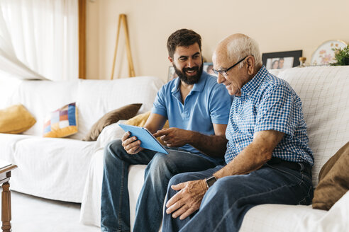 Erwachsener Enkel bringt seinem Großvater den Umgang mit dem Tablet bei - JRFF01426