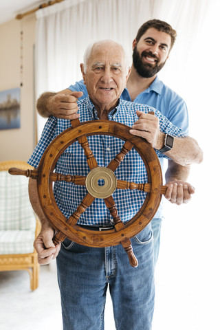 Portrait of grandfather and adult son with helm in the living room stock photo