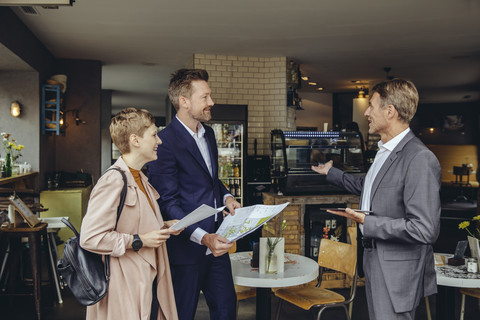 Woman and two businessmen discussing plans in a cafe stock photo