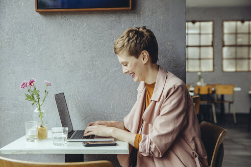 Frau arbeitet in einem Café mit ihrem Laptop - MFF03823