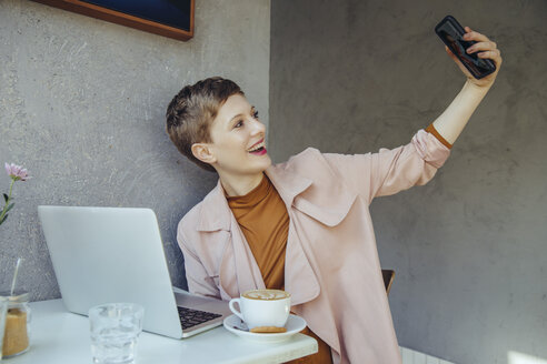 Frau macht ein Selfie mit ihrem Laptop in einem Café - MFF03832