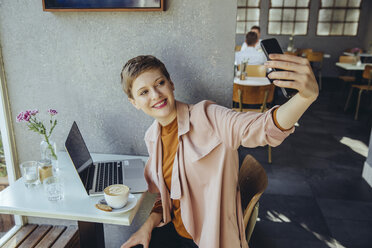 Frau macht ein Selfie mit Kaffee und Laptop in einem Cafe - MFF03833