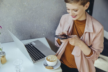 Frau, die ihren Kaffee in einem Café mit dem Smartphone fotografiert - MFF03834