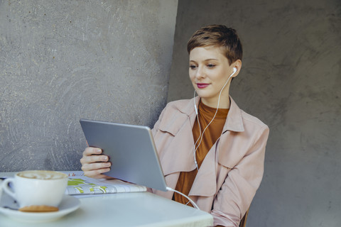 Frau mit Tablet und Kopfhörern in einem Café, lizenzfreies Stockfoto