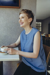 Glückliche Frau mit einer Tasse Kaffee in einem Cafe - MFF03840
