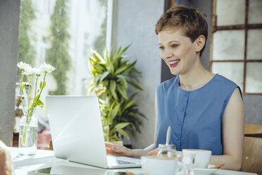 Smiling woman working in cafe with her laptop - MFF03850