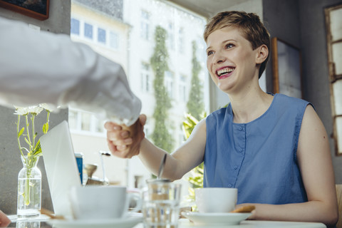 Businessman and businesswoman shaking hands in a cafe stock photo