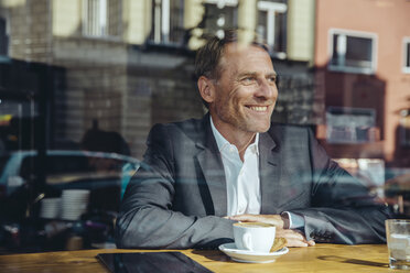 Smiling businessman in cafe looking out of window - MFF03866