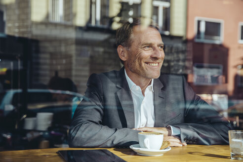 Lächelnder Geschäftsmann im Café, der aus dem Fenster schaut - MFF03866