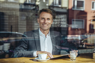 Portrait of smiling businessman with tablet in cafe - MFF03868