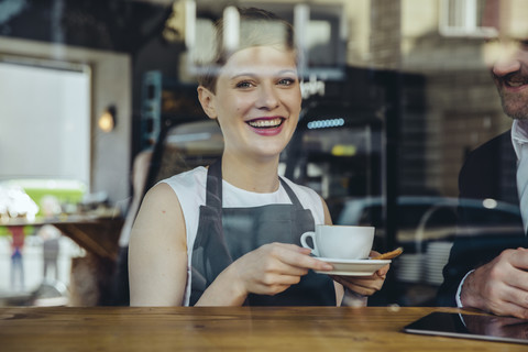 Smiling waitress serving coffee to customer in cafe stock photo