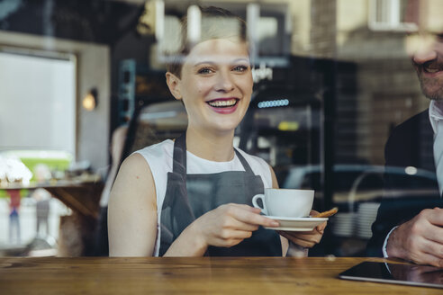 Lächelnde Kellnerin, die einem Kunden in einem Café Kaffee serviert - MFF03871
