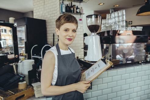 Portrait of waitress holding menu in a cafe - MFF03874