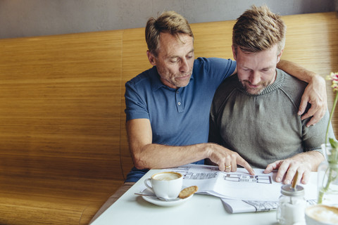 Gay couple looking at constructions plans for their home in cafe stock photo