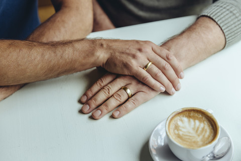Close-up of men's hands with wedding rings and a cup of coffee stock photo