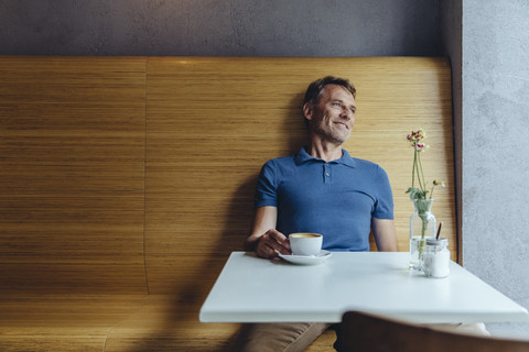Entspannter reifer Mann sitzt in einem Cafe, lizenzfreies Stockfoto