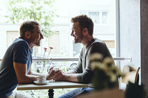Homosexuelles Paar, das sich im Café an den Händen hält und sich gegenseitig ansieht - MFF03909