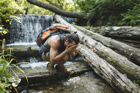 Junger Mann auf einer Wanderung erfrischt sich an einem Wasserfall - VPIF00024